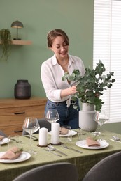 Photo of Happy young woman setting table for dinner at home