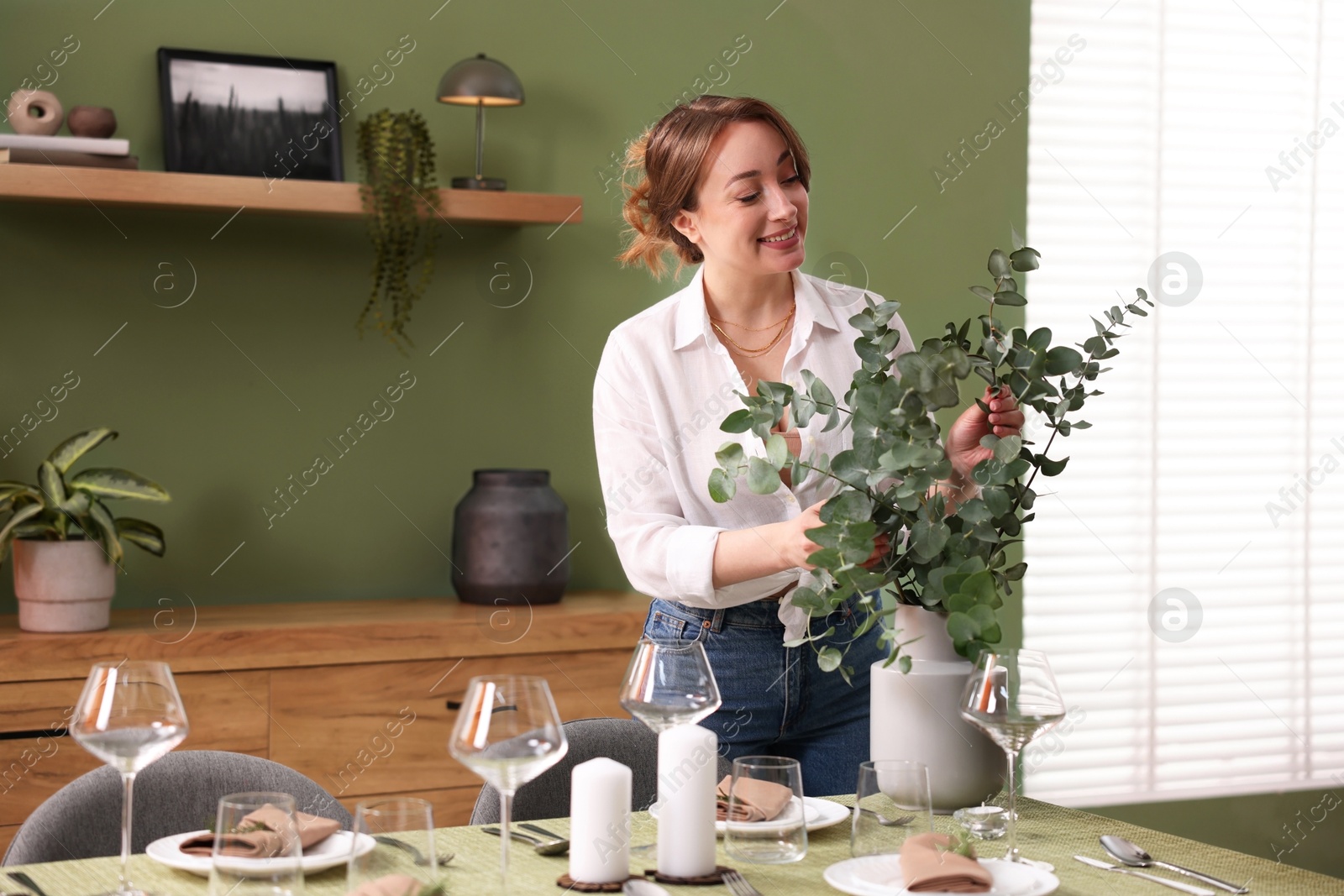 Photo of Happy young woman setting table for dinner at home