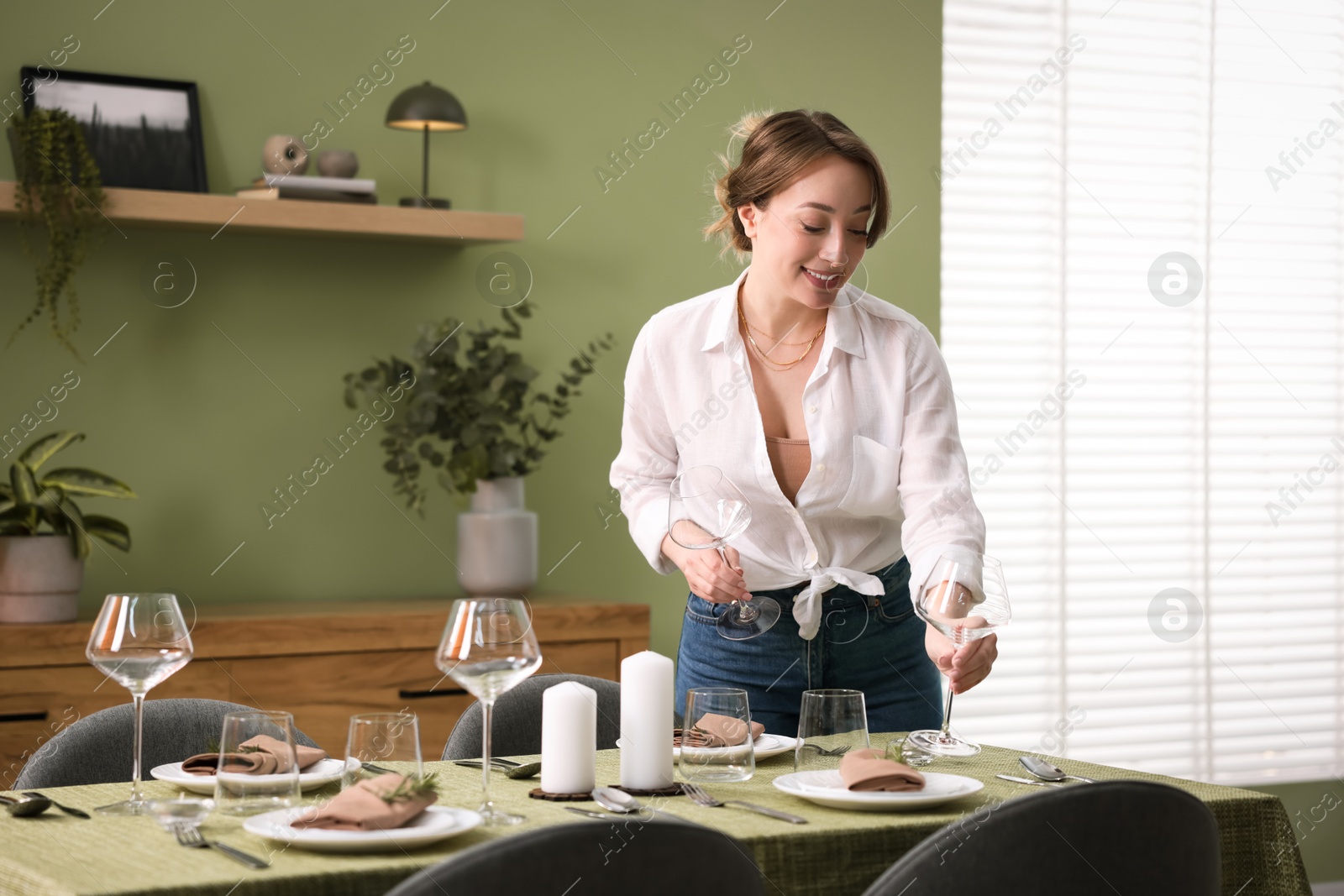 Photo of Happy young woman setting table for dinner at home