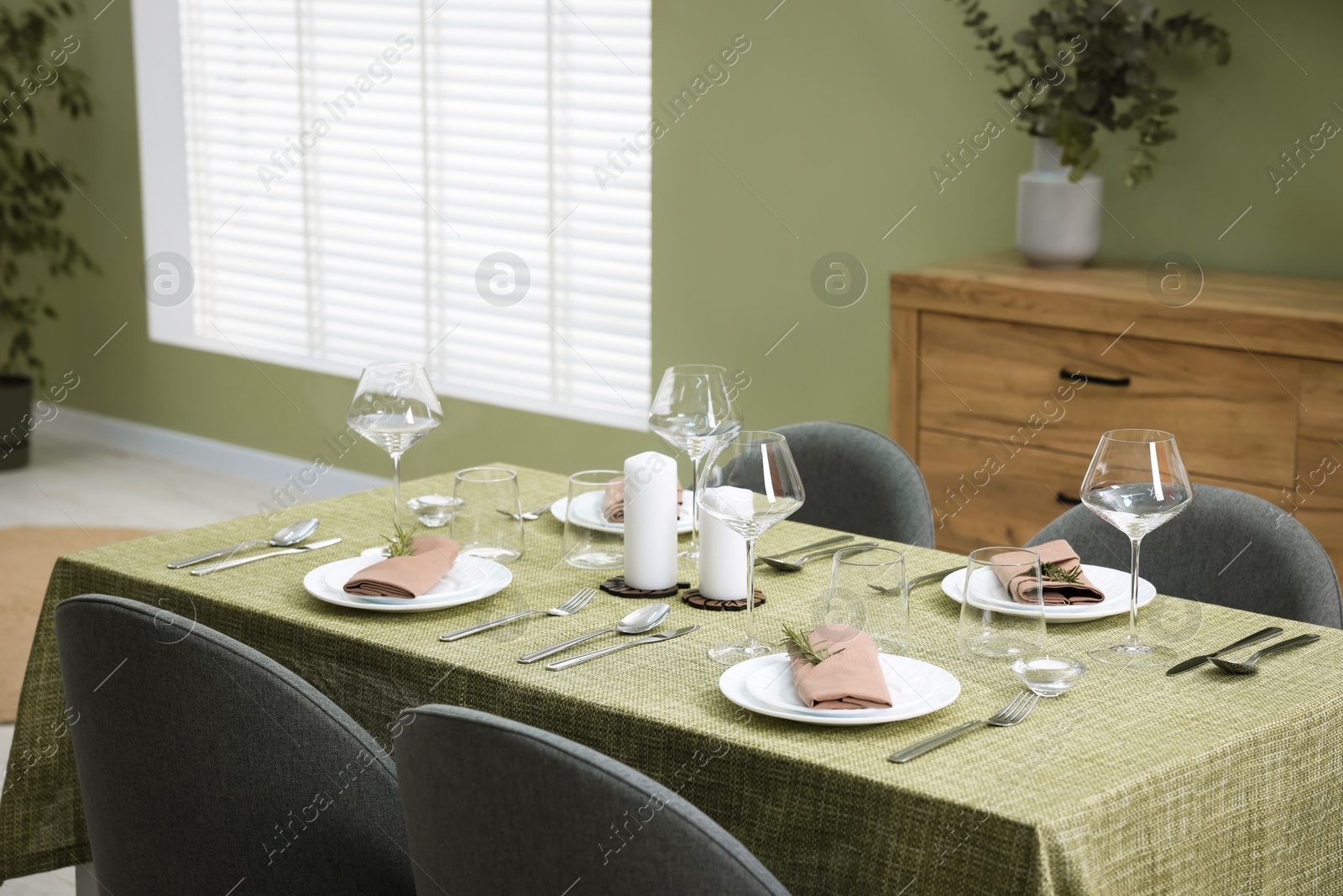 Photo of Stylish table setting with olive tablecloth, glasses and candles indoors