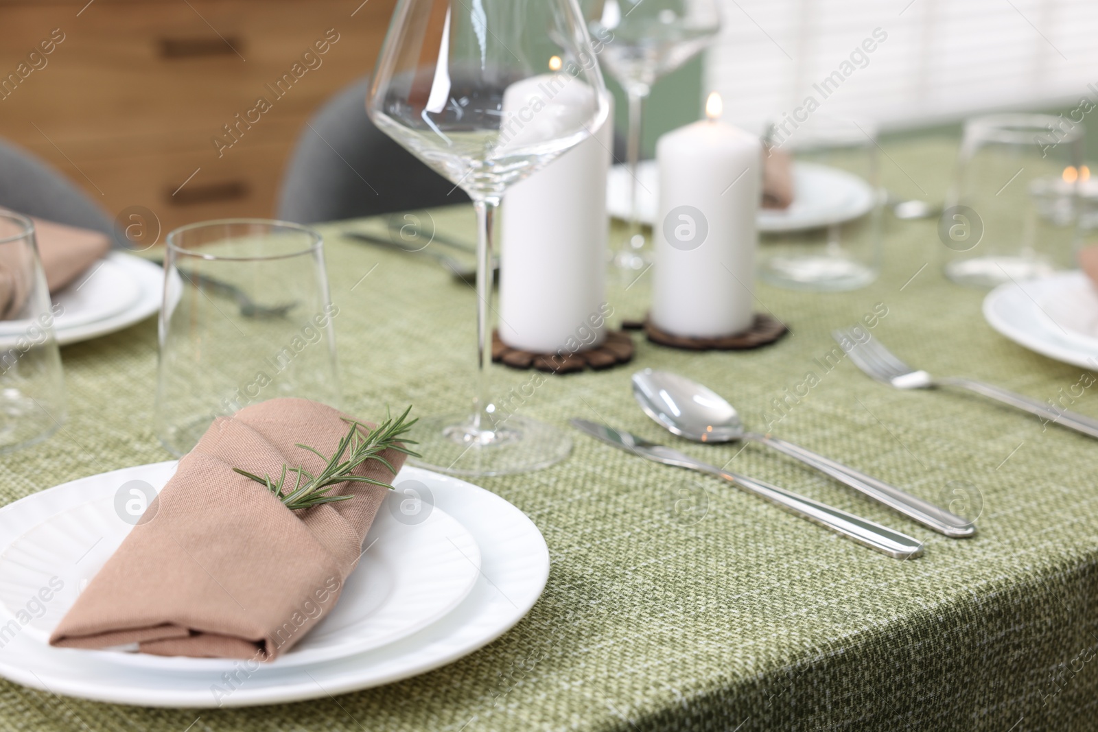 Photo of Stylish table setting with olive tablecloth, glasses and candles indoors, closeup