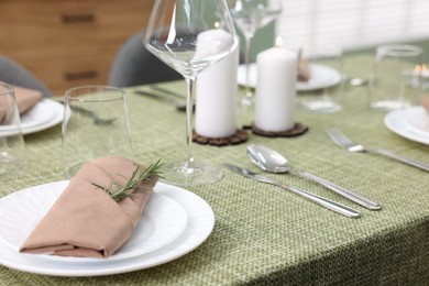 Photo of Stylish table setting with olive tablecloth, glasses and candles indoors, closeup