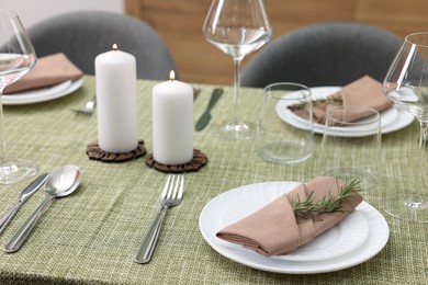 Photo of Stylish table setting with olive tablecloth, glasses and candles indoors, closeup