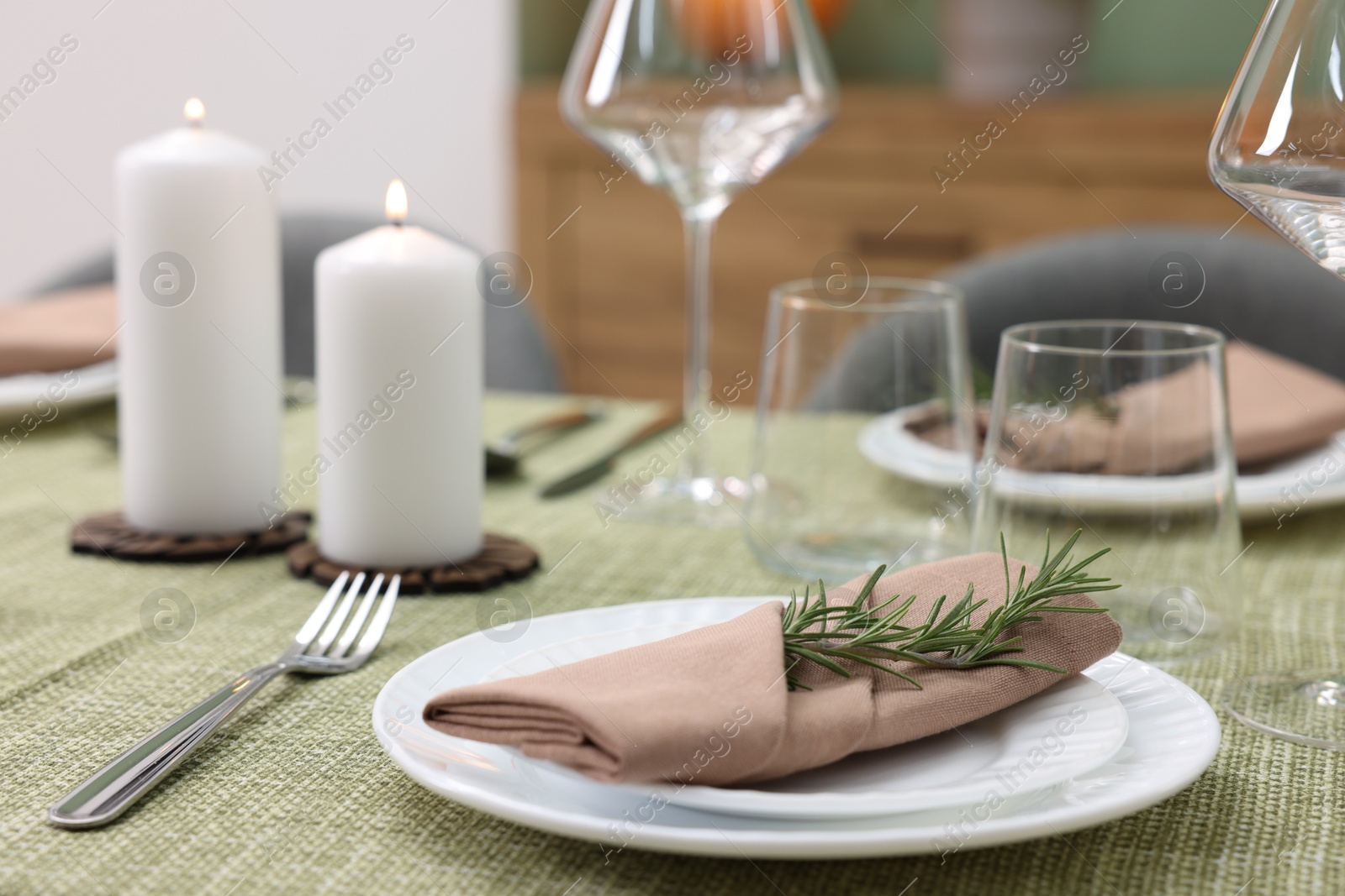 Photo of Stylish table setting with olive tablecloth, glasses and candles indoors, closeup