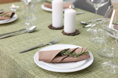 Photo of Stylish table setting with olive tablecloth, glasses and candles indoors, closeup