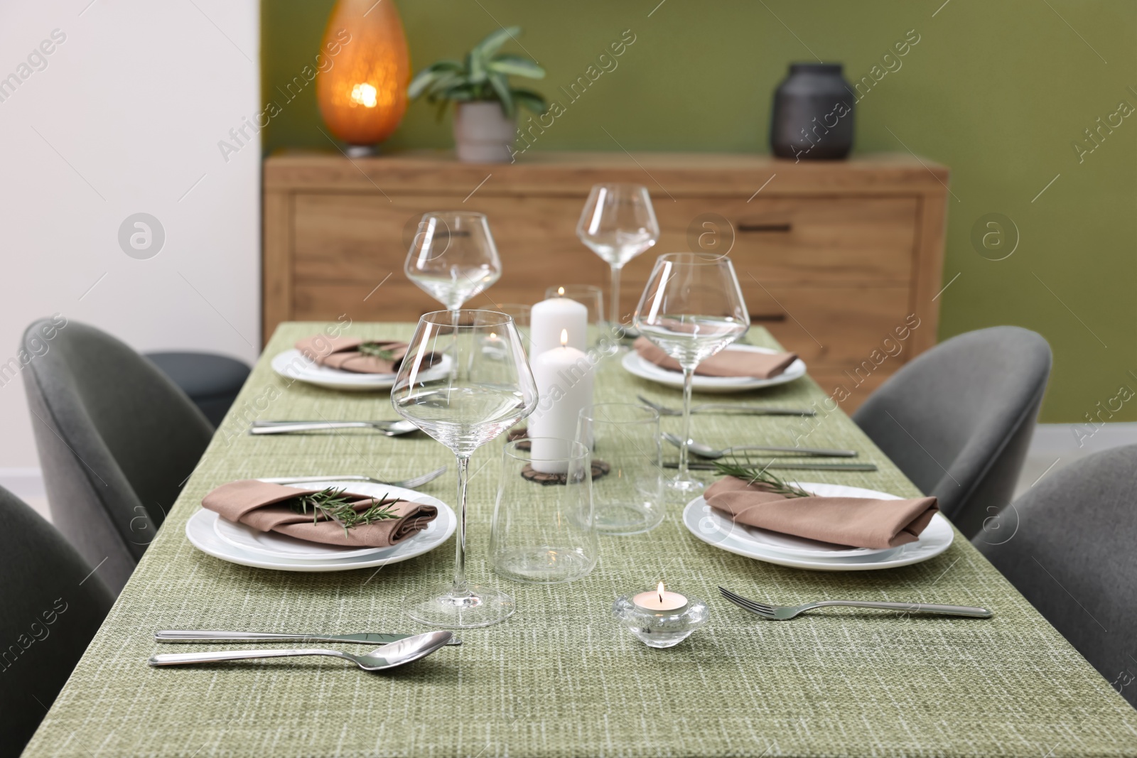 Photo of Stylish table setting with olive tablecloth, glasses and candles indoors