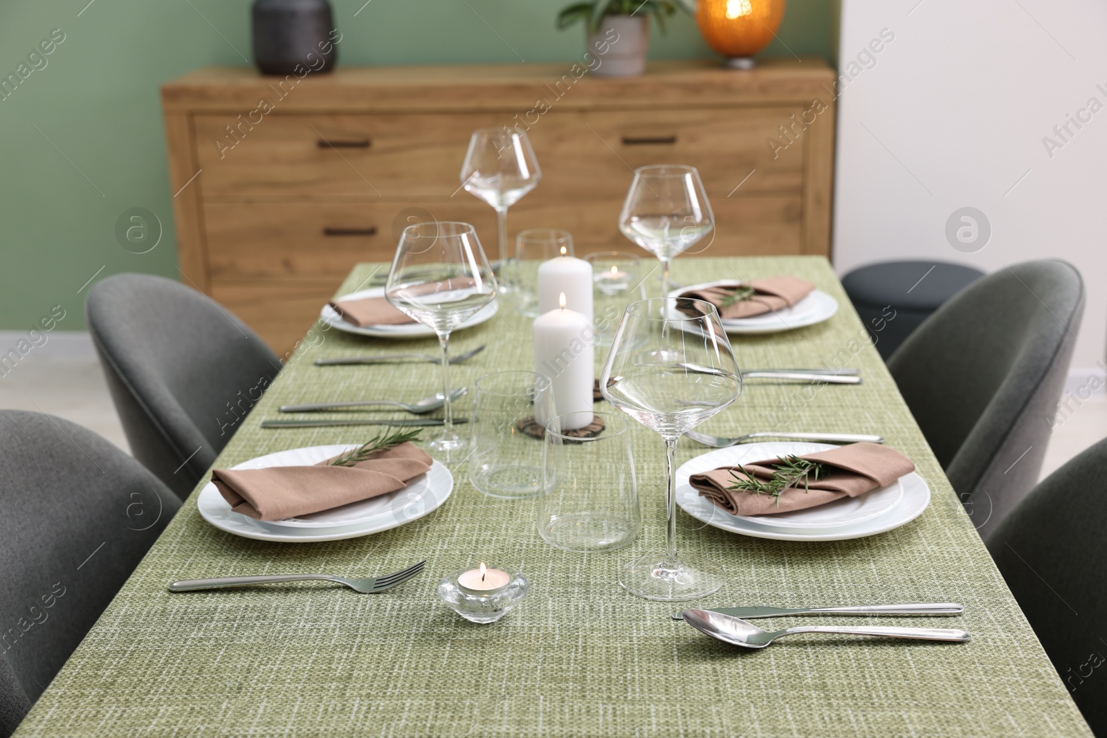 Photo of Stylish table setting with olive tablecloth, glasses and candles indoors