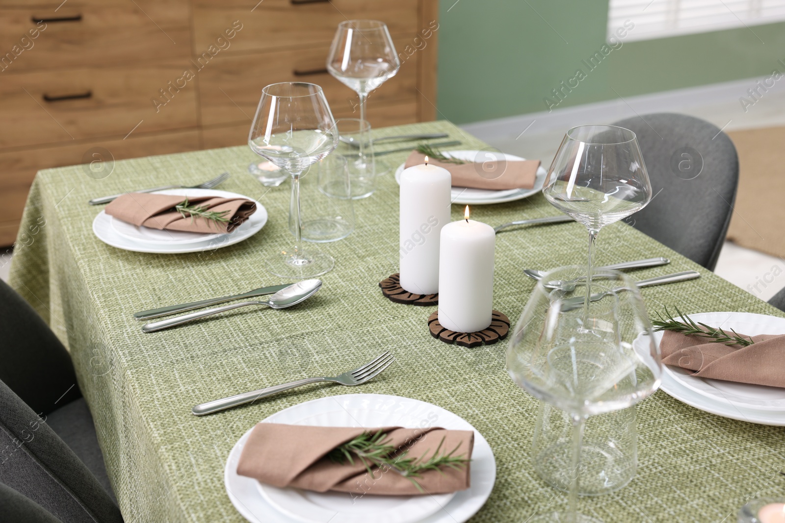 Photo of Stylish table setting with olive tablecloth, glasses and candles indoors