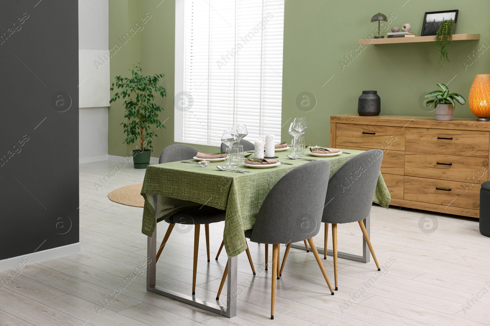 Photo of Stylish table setting with olive tablecloth, glasses and candles in dining room