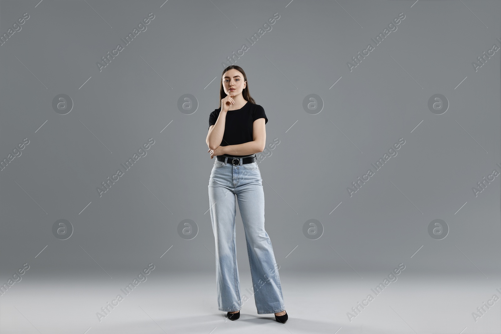 Photo of Beautiful young woman in stylish jeans on grey background