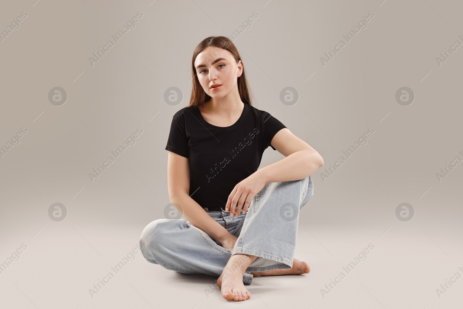 Photo of Beautiful young woman in stylish jeans on grey background