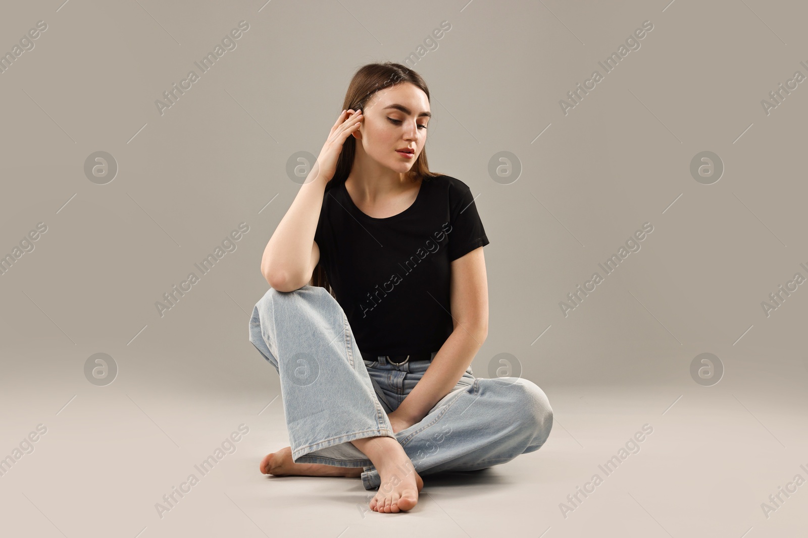 Photo of Beautiful young woman in stylish jeans on grey background