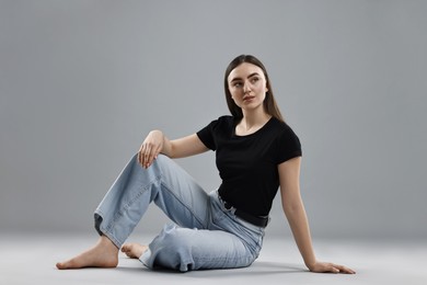 Photo of Beautiful young woman in stylish jeans on grey background