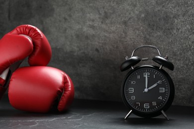 Photo of Alarm clock and boxing gloves on grey background