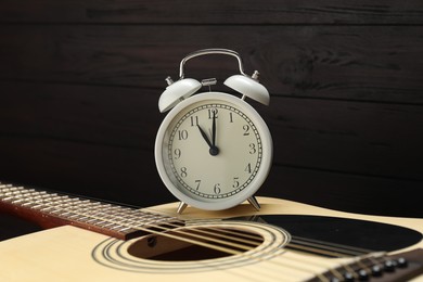 Photo of Alarm clock and guitar on wooden background