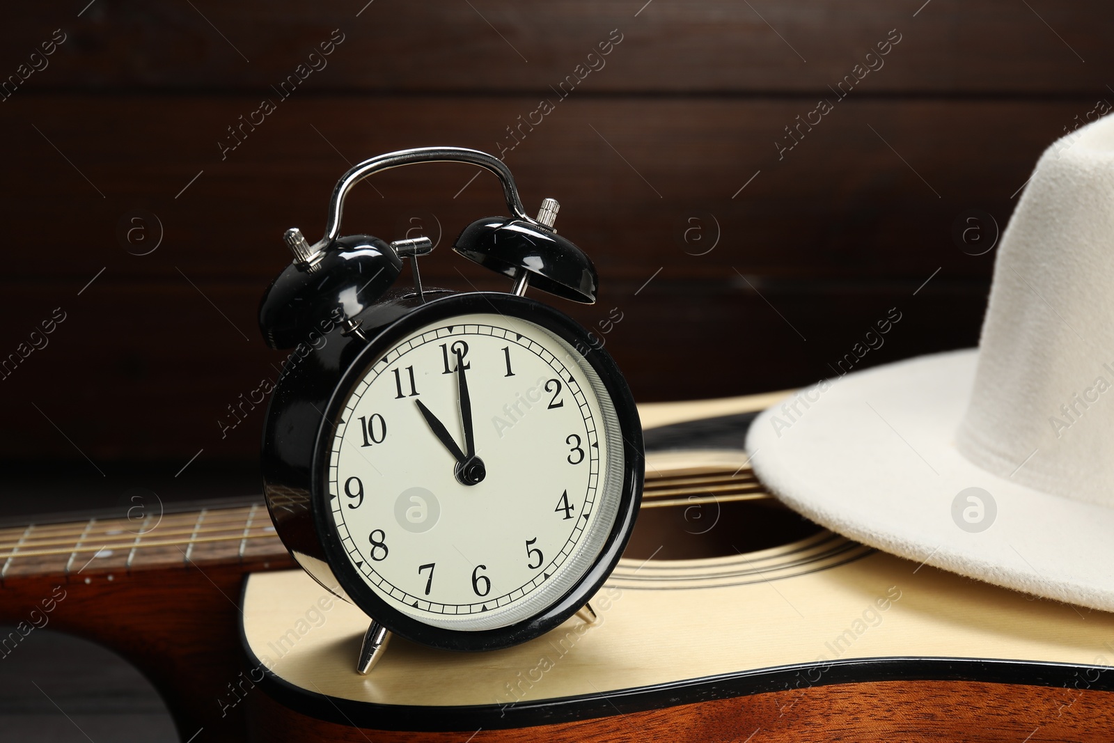 Photo of Alarm clock, hat and guitar on wooden background