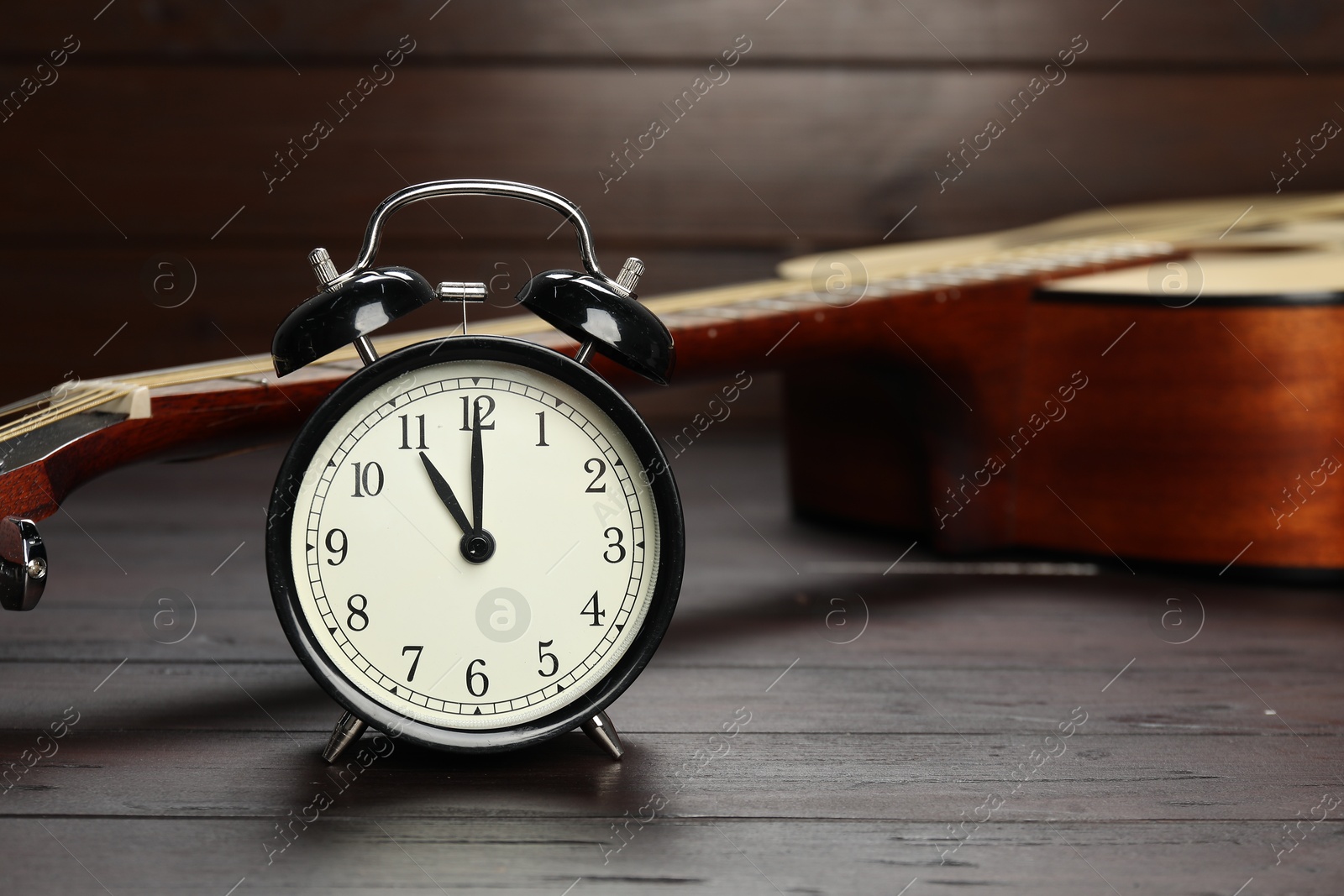 Photo of Alarm clock and guitar on wooden background