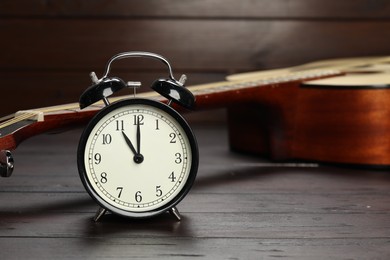 Photo of Alarm clock and guitar on wooden background