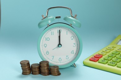 Photo of Alarm clock, coins and calculator on light blue background