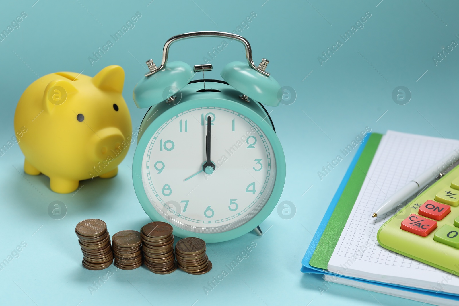 Photo of Alarm clock, coins, piggybank, notebook and calculator on light blue background