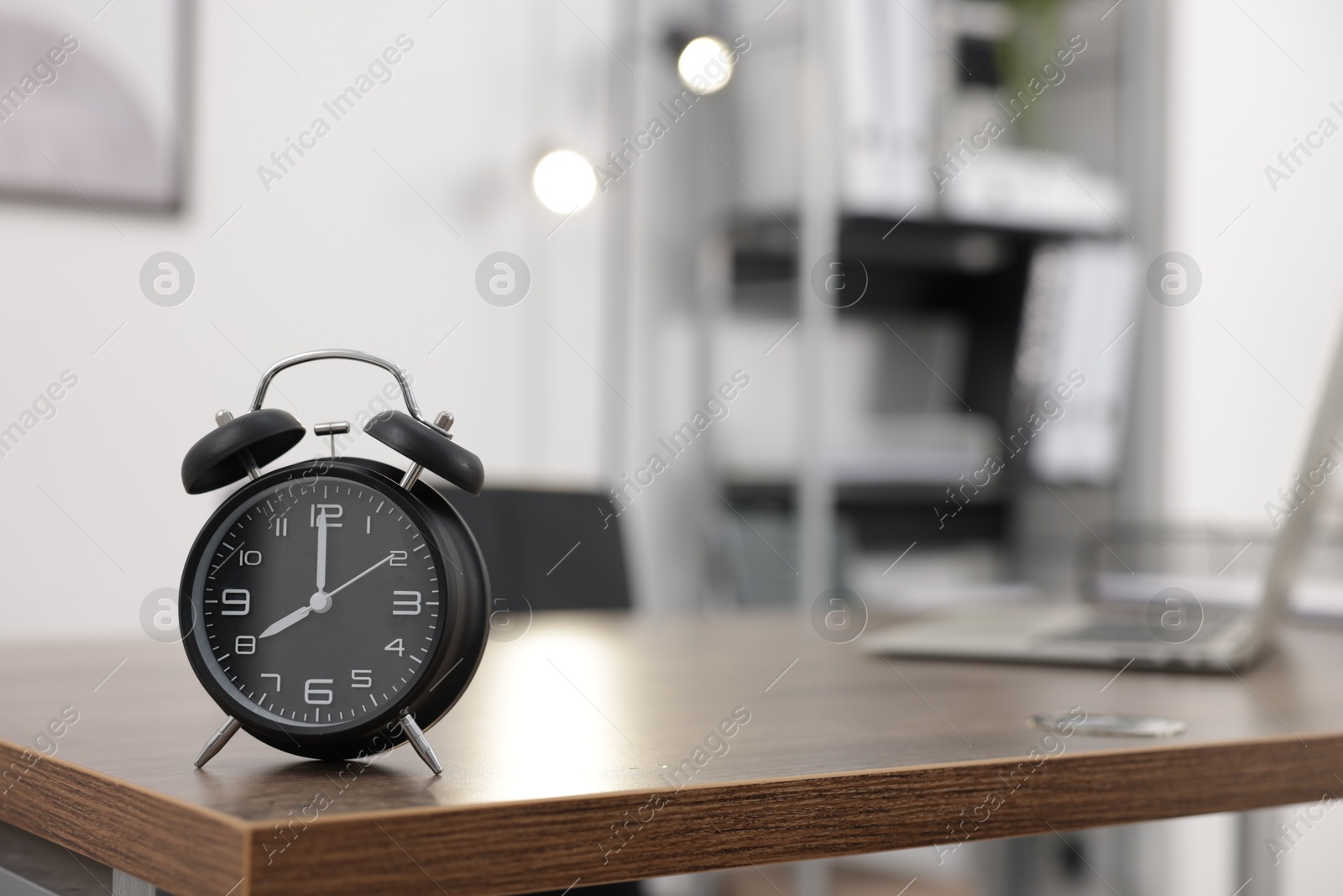 Photo of Alarm clock on wooden desk in office. Space for text