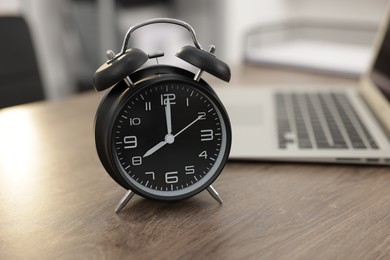 Photo of Alarm clock on wooden desk in office