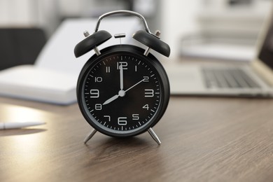 Photo of Alarm clock on wooden desk in office