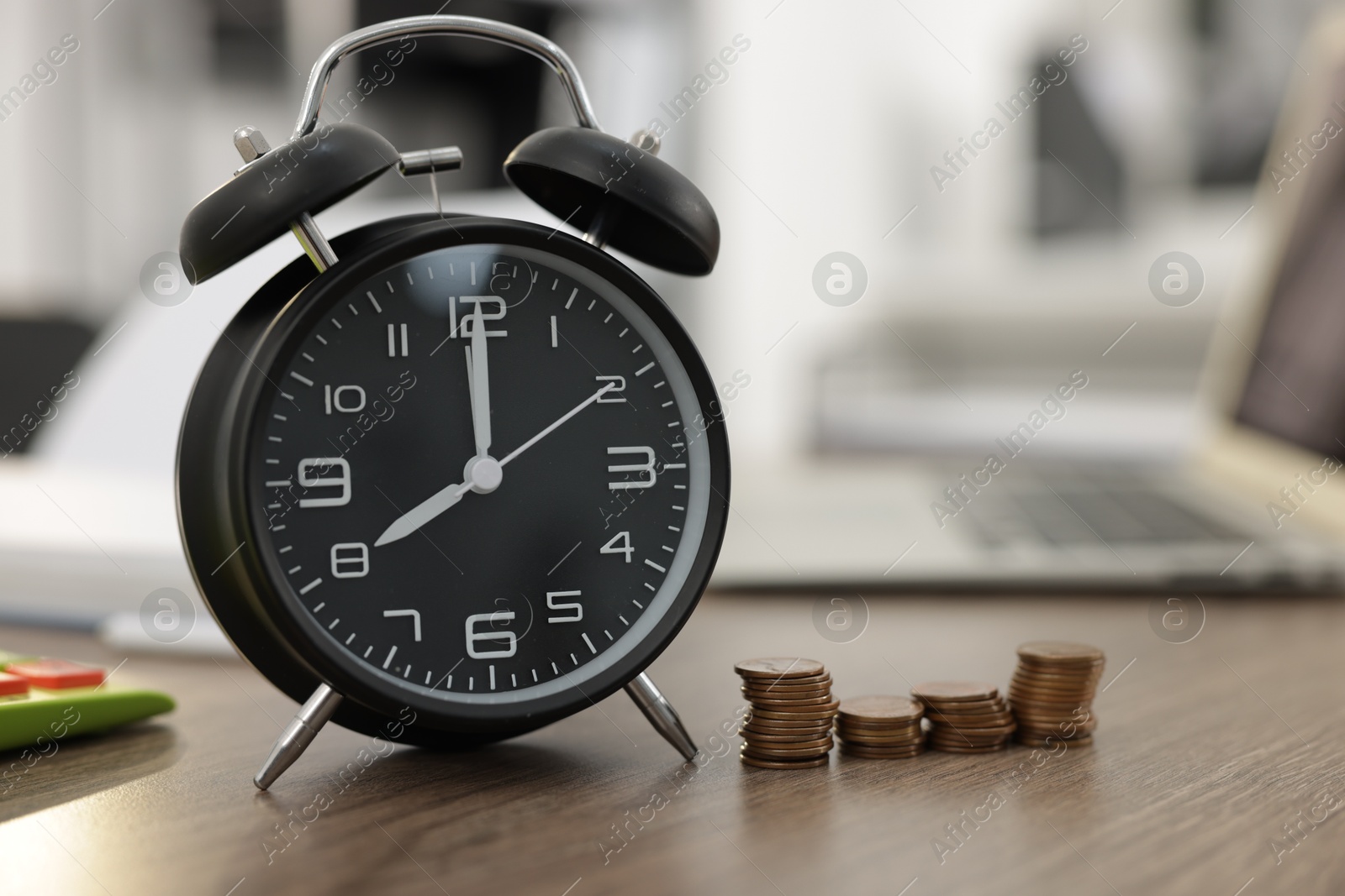 Photo of Alarm clock and coins on wooden desk in office. Space for text