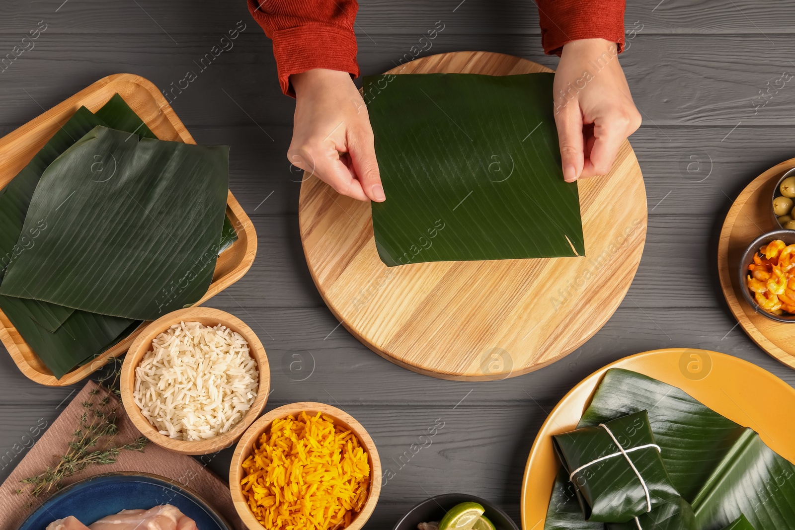 Photo of Woman with banana leaf at wooden table with different products, top view. Healthy eco serving