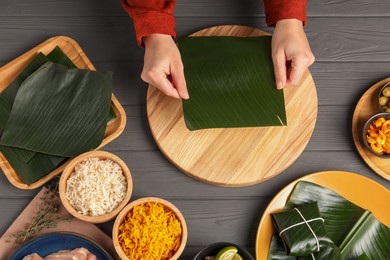 Photo of Woman with banana leaf at wooden table with different products, top view. Healthy eco serving