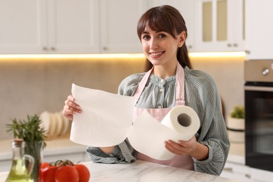 Photo of Smiling woman using paper towels at white marble table in kitchen