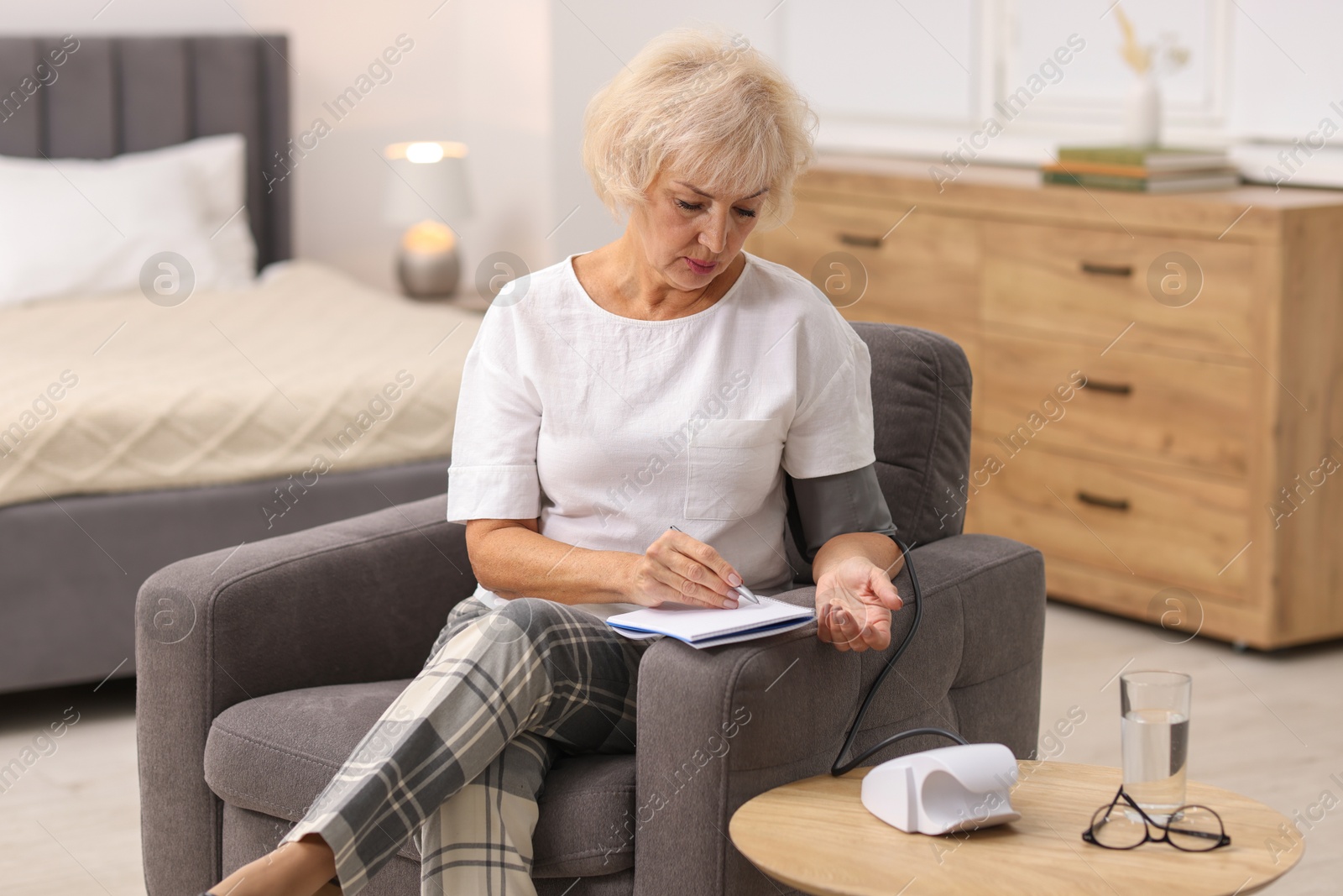 Photo of Senior woman writing results of blood pressure measurement at home