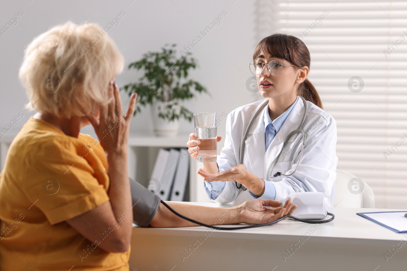 Photo of Doctor measuring senior woman's blood pressure during appointment in hospital