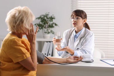 Photo of Doctor measuring senior woman's blood pressure during appointment in hospital