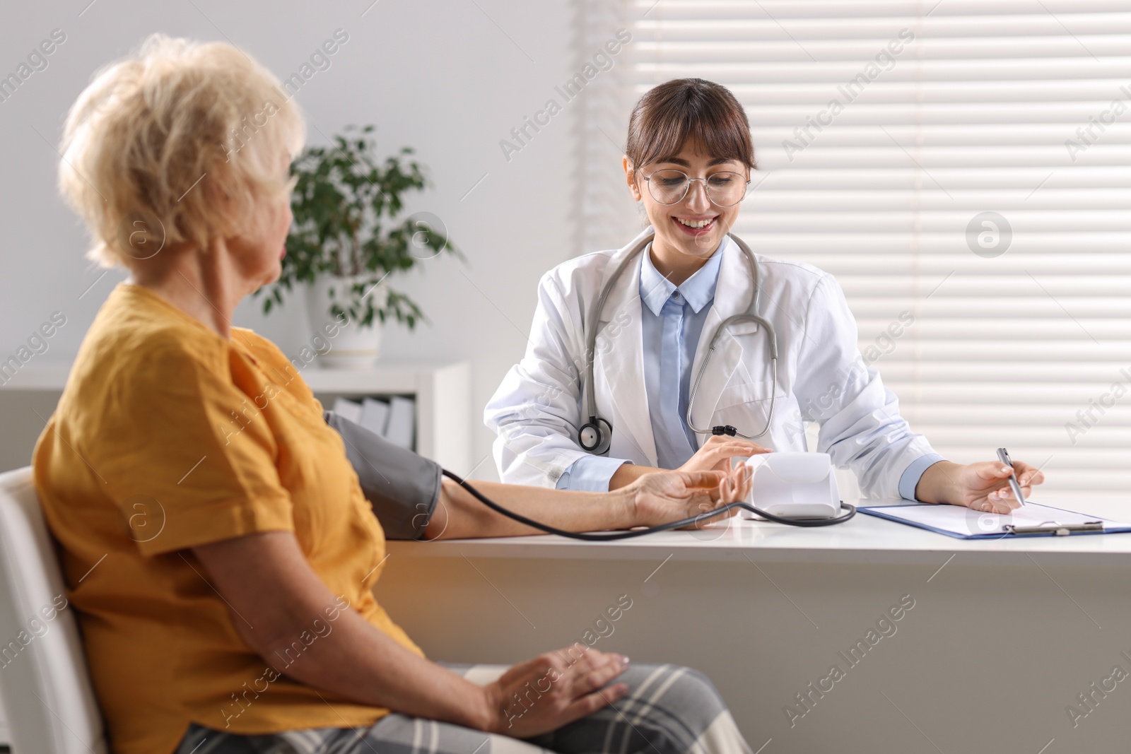 Photo of Doctor measuring senior woman's blood pressure during appointment in hospital