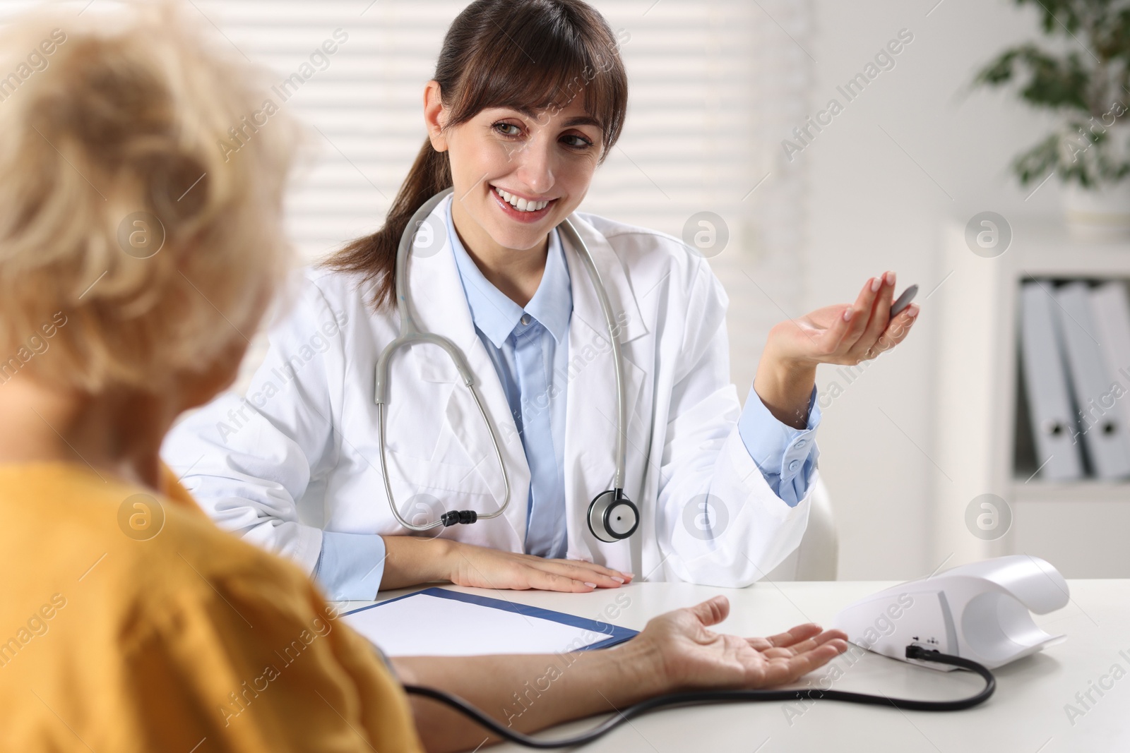 Photo of Doctor measuring senior woman's blood pressure during appointment in hospital