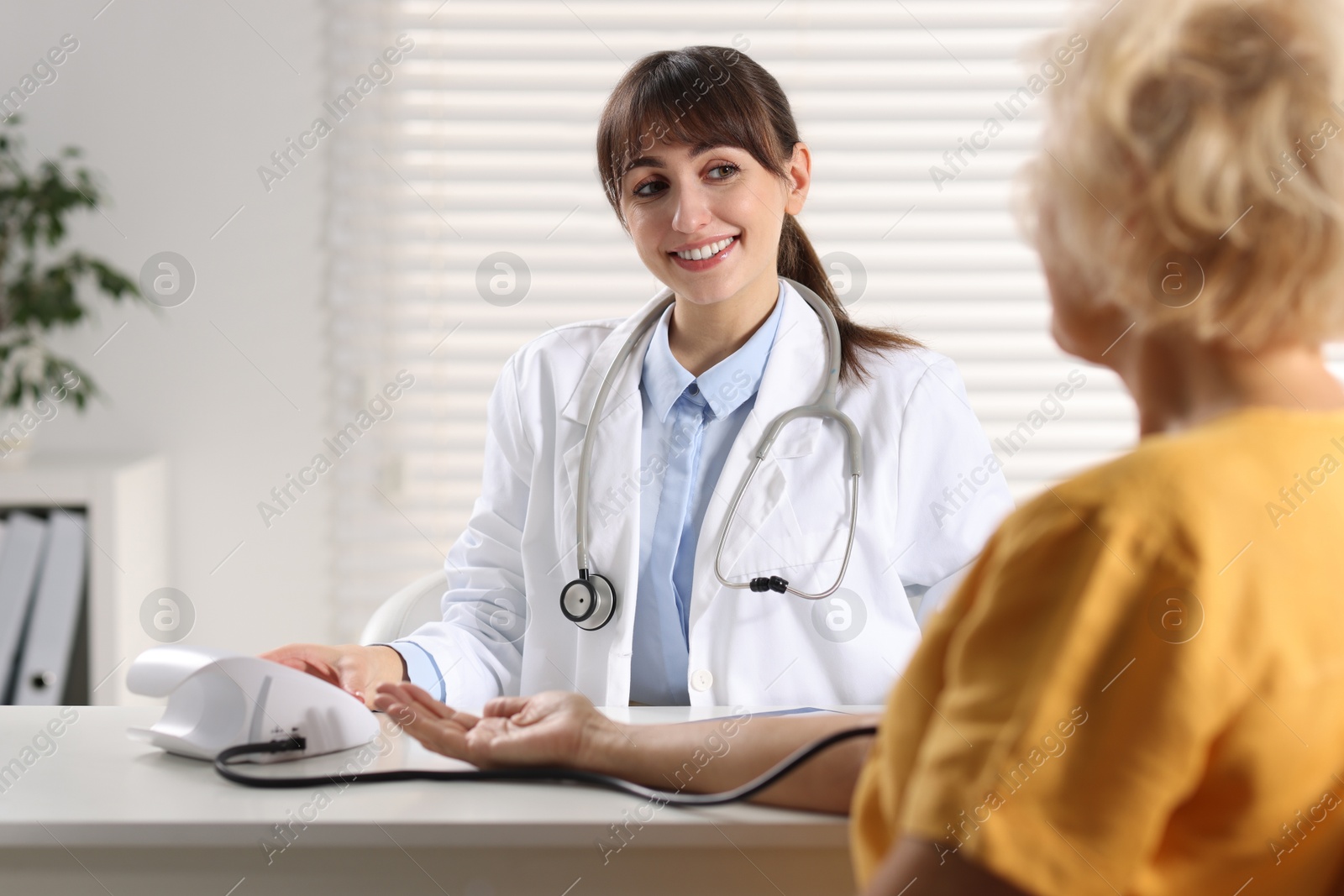 Photo of Doctor measuring senior woman's blood pressure during appointment in hospital