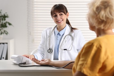 Doctor measuring senior woman's blood pressure during appointment in hospital