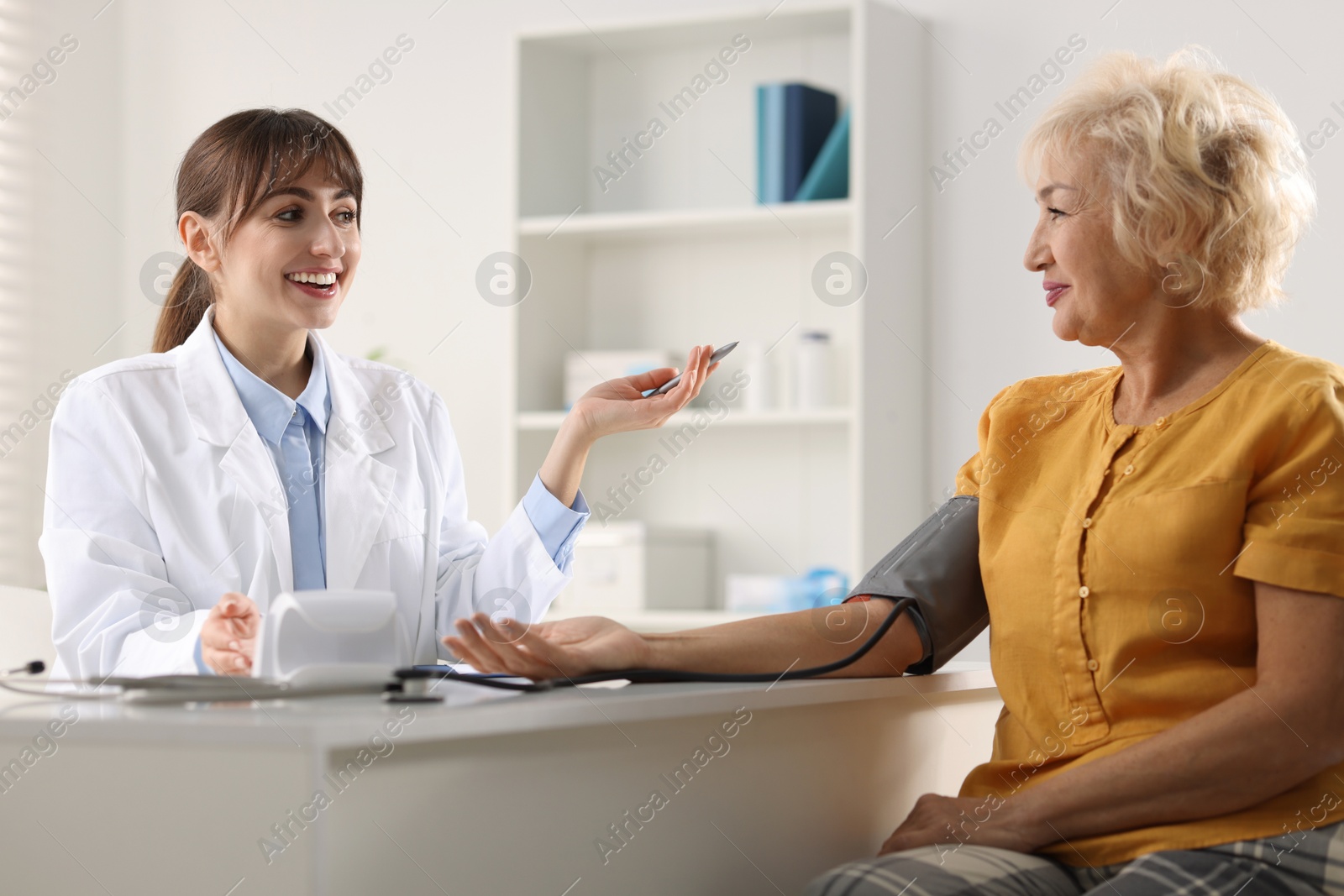 Photo of Doctor measuring senior woman's blood pressure during appointment in hospital