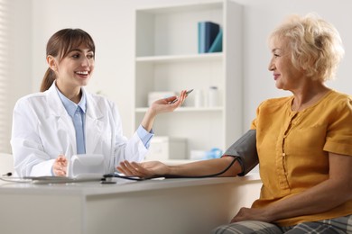 Doctor measuring senior woman's blood pressure during appointment in hospital