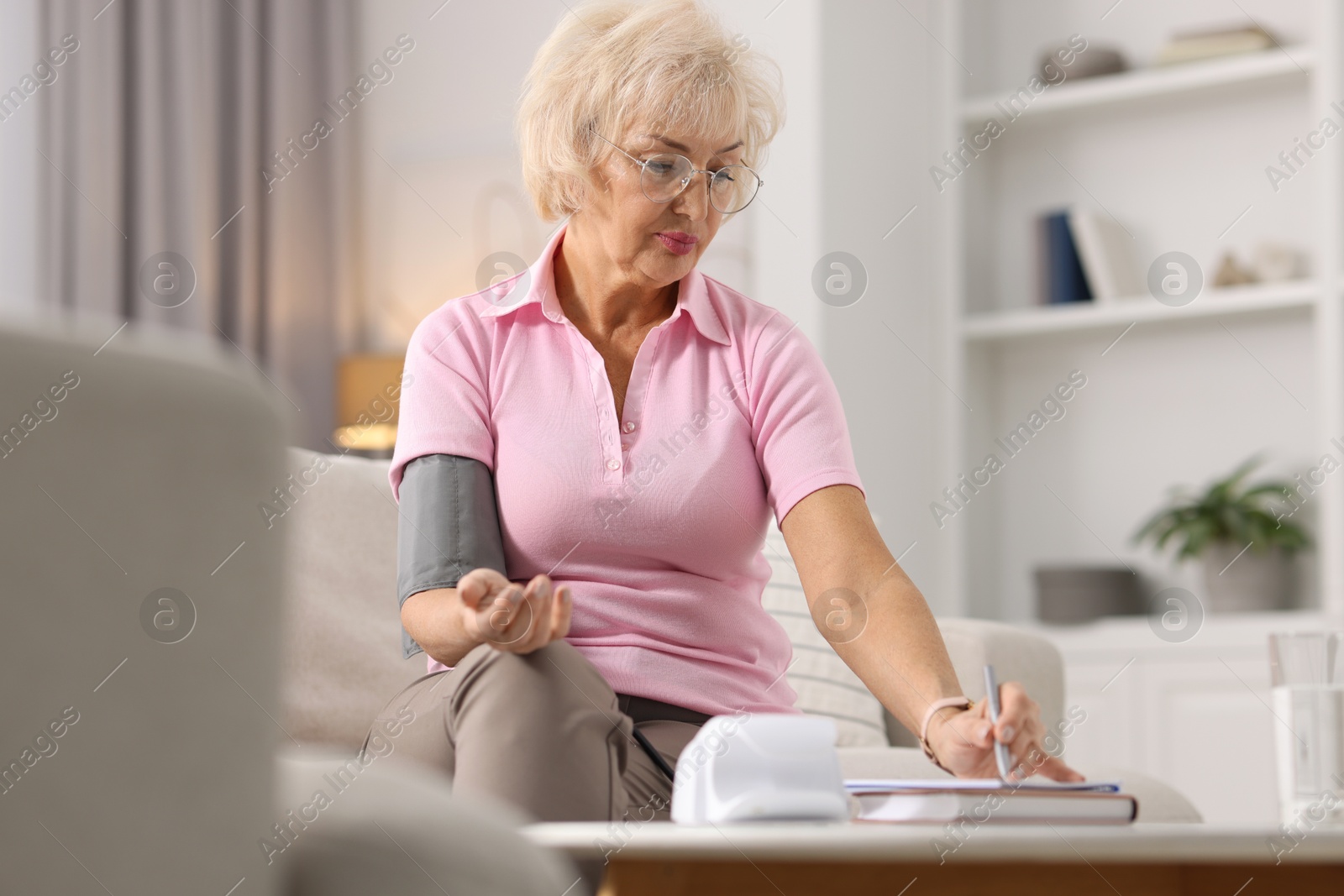 Photo of Senior woman writing results of blood pressure measurement at home