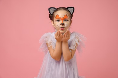 Photo of Cute girl with painted face and ears as cat on pink background