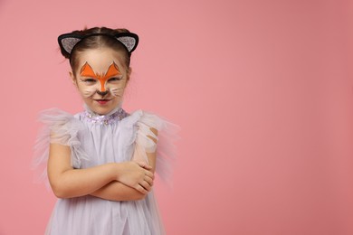 Cute girl with painted face and ears as cat on pink background, space for text