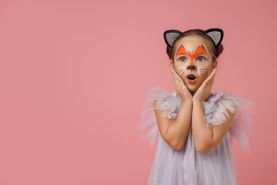 Cute girl with painted face and ears as cat on pink background, space for text