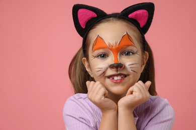 Cute girl with painted face and ears as cat on pink background, space for text