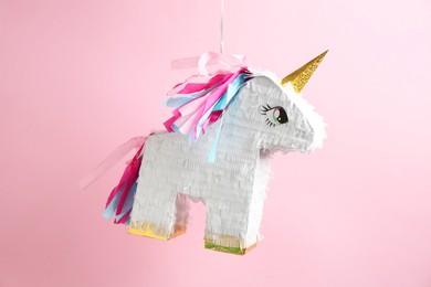 Photo of Bright pinata in shape of unicorn hanging on pink background