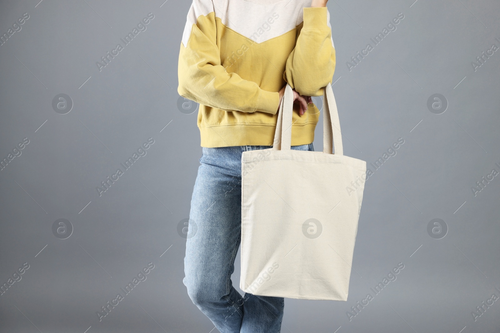 Photo of Woman with blank shopper bag on grey background, closeup. Mockup for design