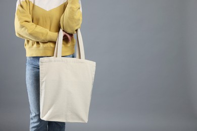 Woman with blank shopper bag on grey background, closeup. Mockup for design