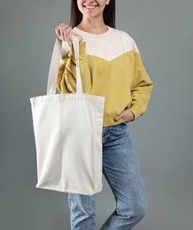 Woman with blank shopper bag on grey background, closeup. Mockup for design