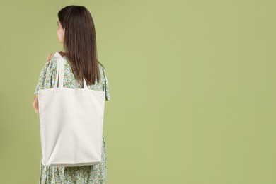 Woman with blank shopper bag on color background, back view. Mockup for design